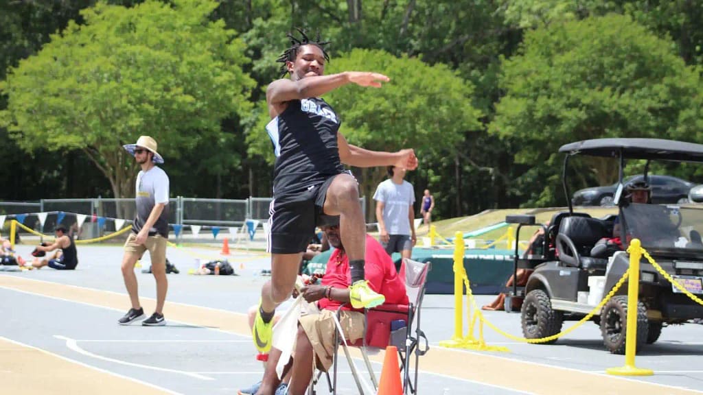 athlete appears to be hurdling over a spectator