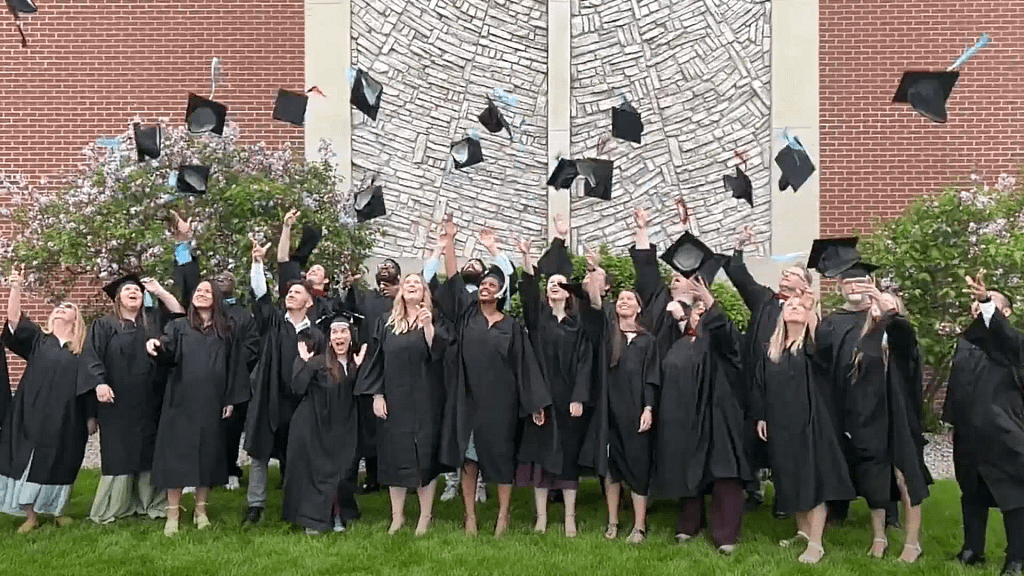 A group of Grace Graduates tossing their hats in the air.