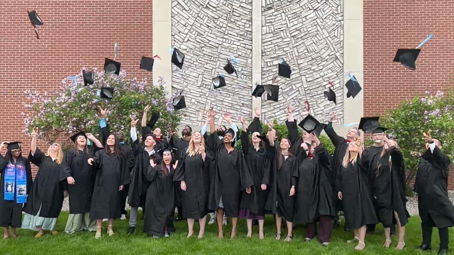 A group of Grace Graduates tossing their hats in the air.