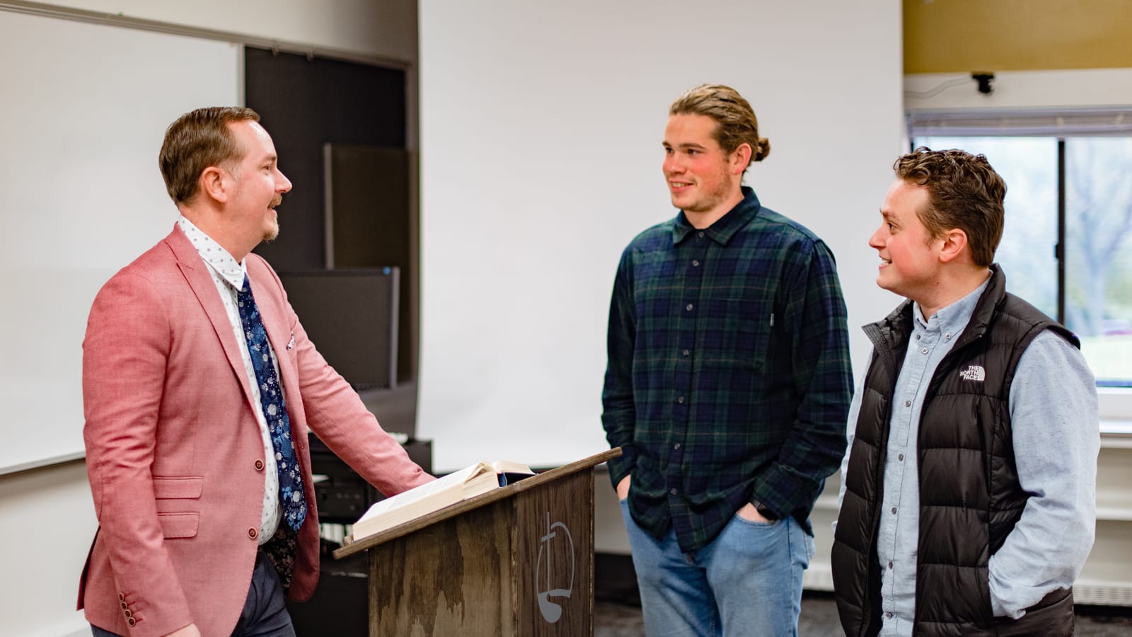 On-Campus-Biblical-Studies4 Two students talking to a professor in a classroom