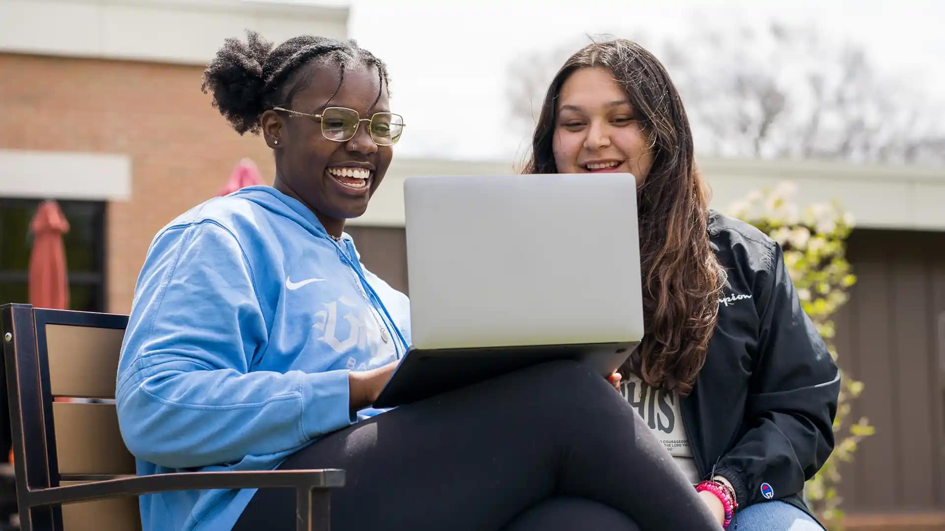 Loans Two Grace students sitting outside and looking at a laptop