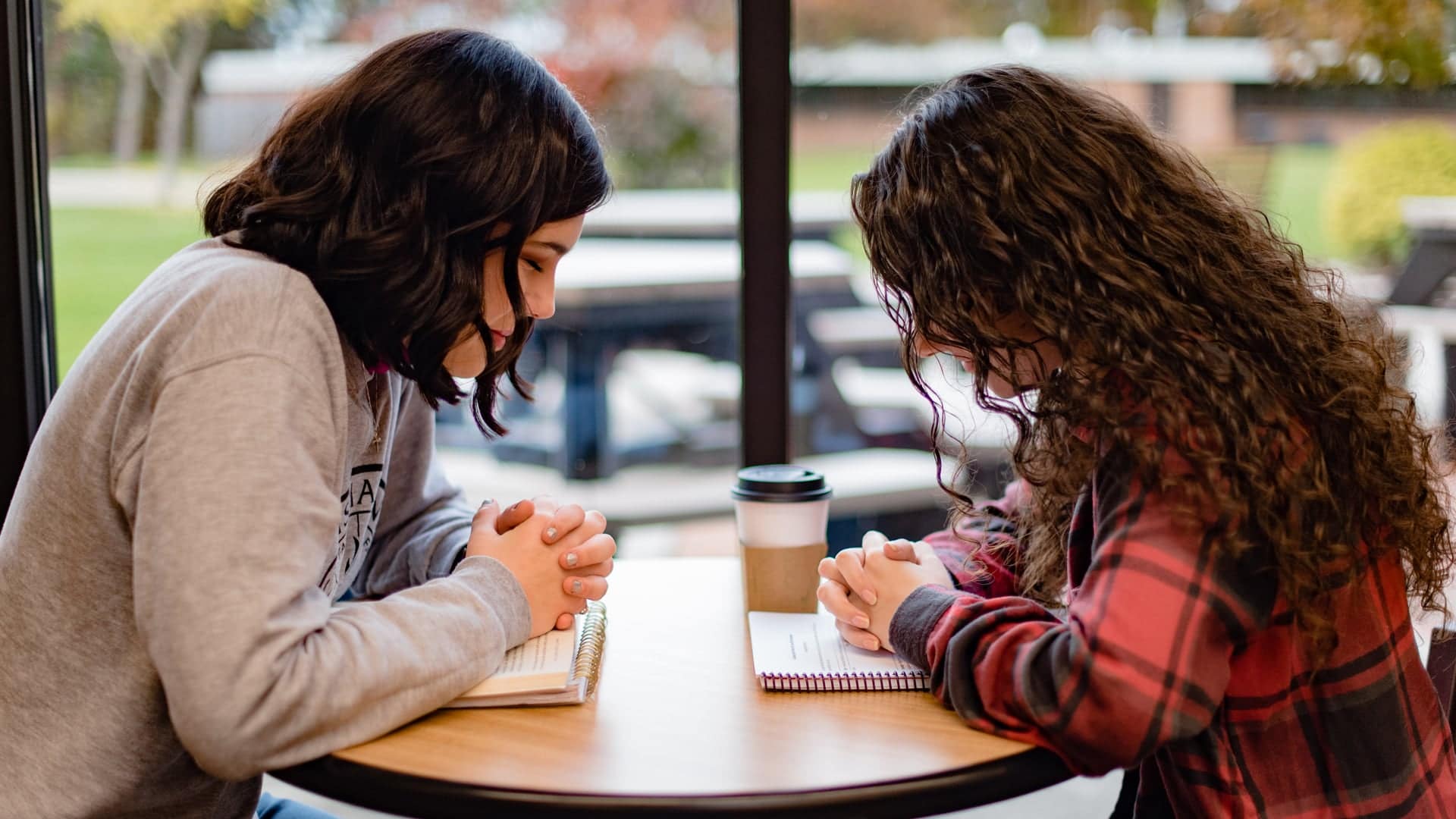 Psychology Two Psychology students praying at table in the Commons.