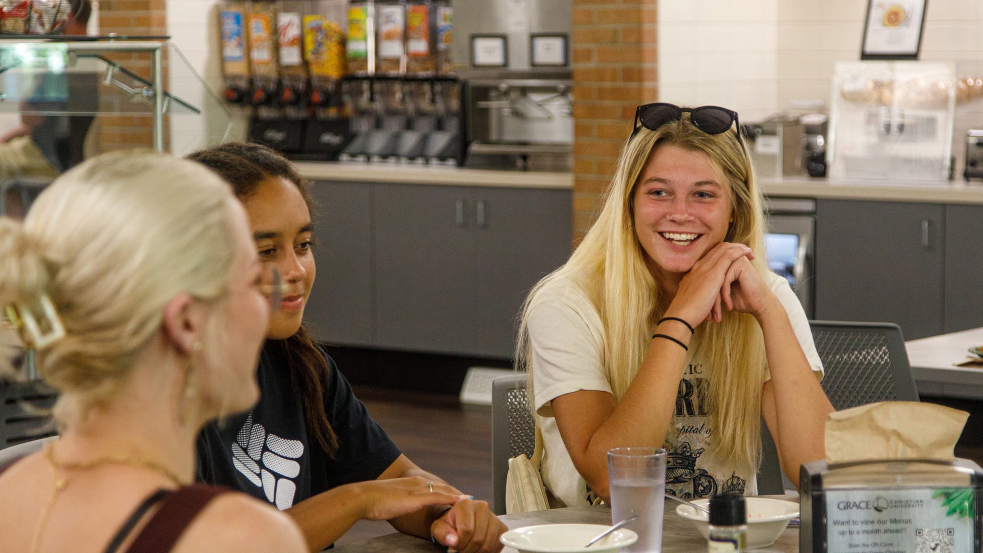 Campus-Tour-Dining-Room Happy Grace Students sit around a table in the dining hall, at Grace Christian University, during a Campus Tour