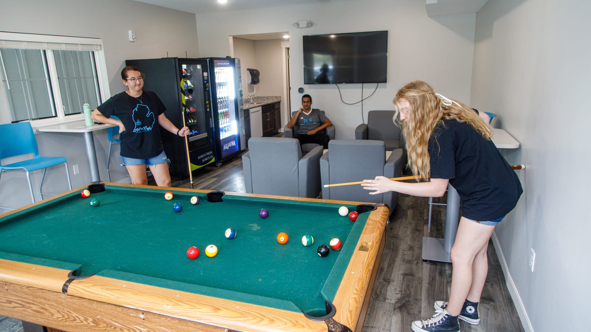 Hilltop-Community-Room Grace students relaxing on chairs and playing pool in the Hilltop Community Room.
