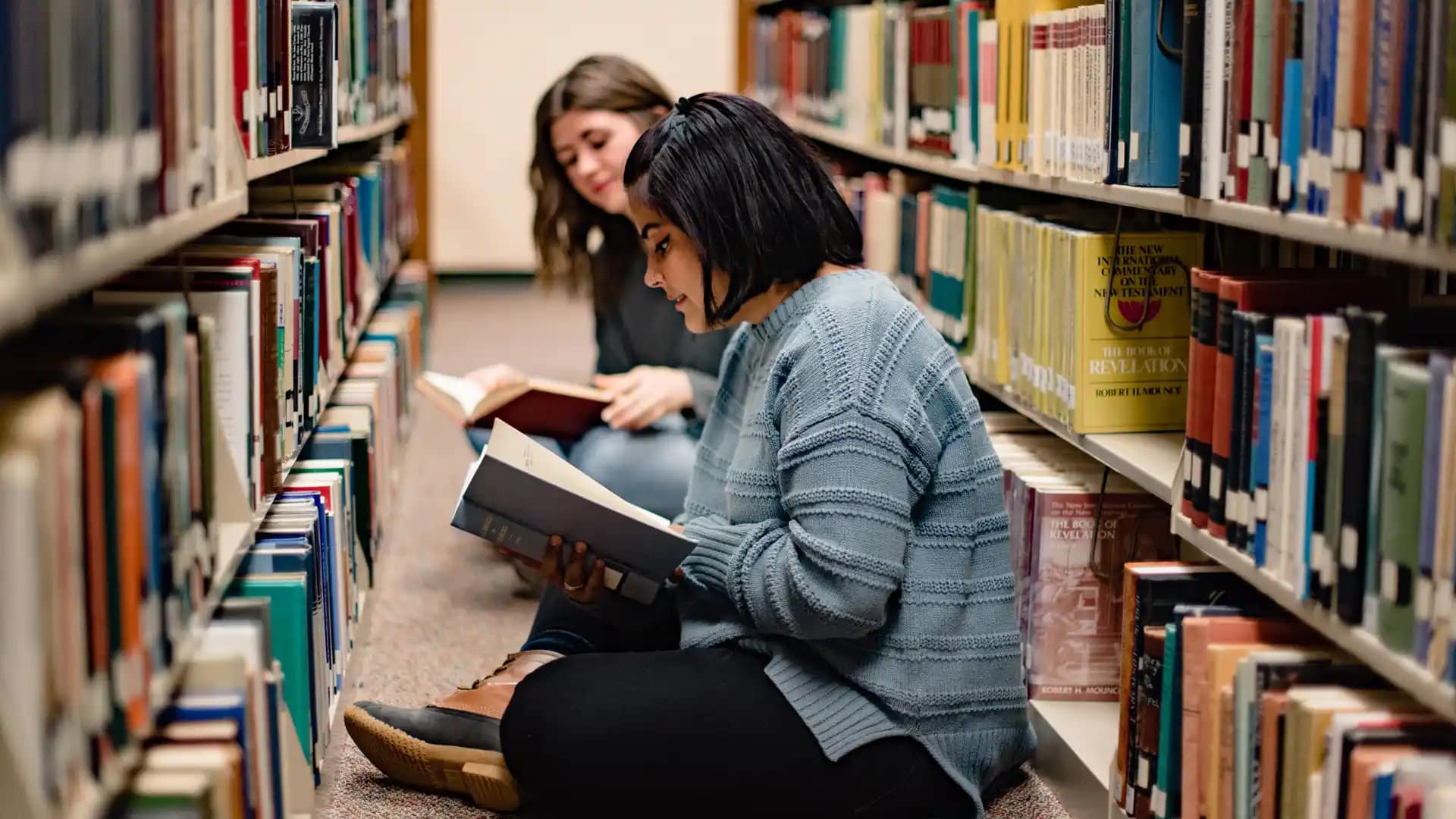 Library Students sitting on the floor in the library, reading