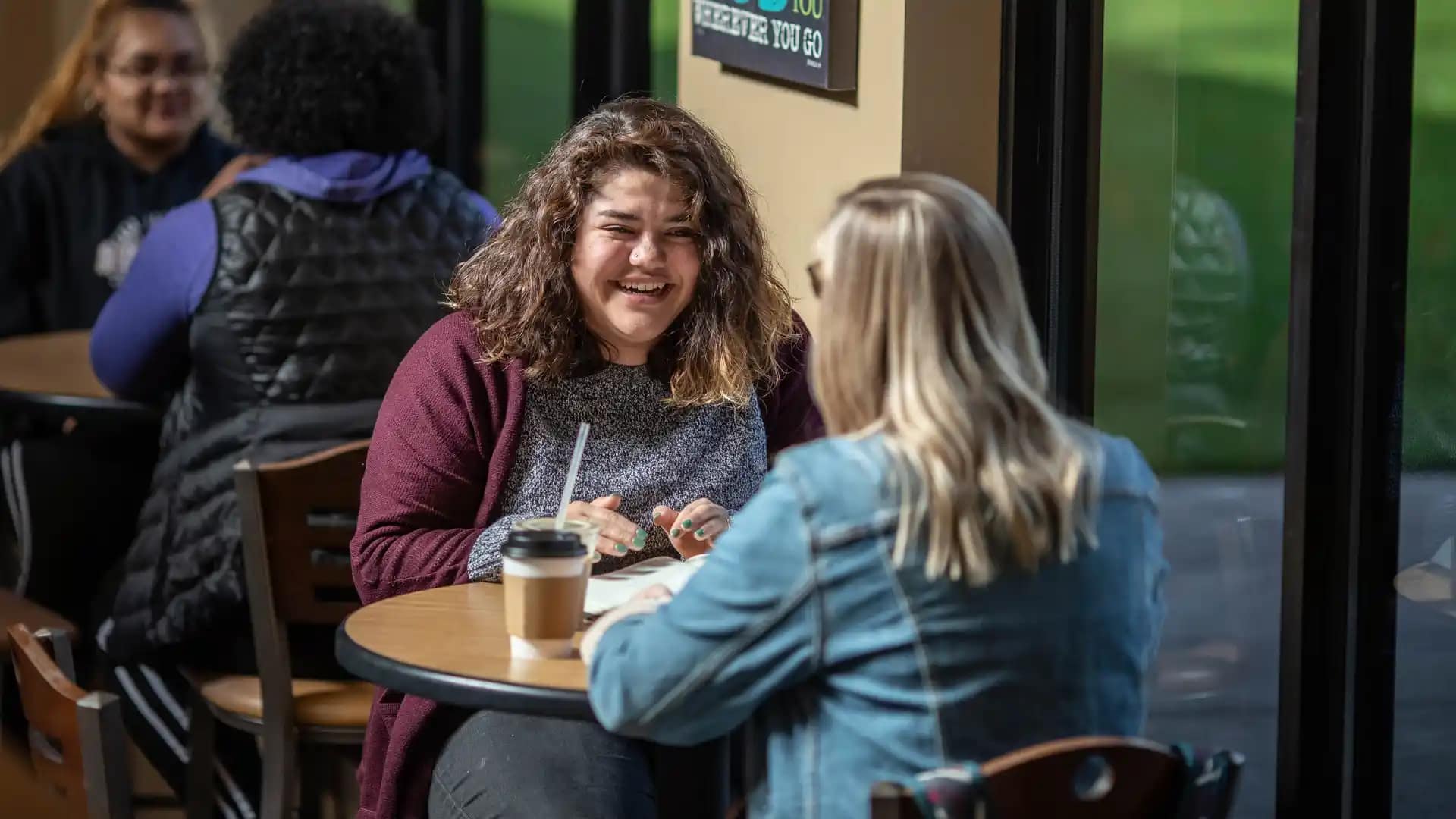 Student-Account-Payment Two female Grace students sitting at a table in the Student Commons.