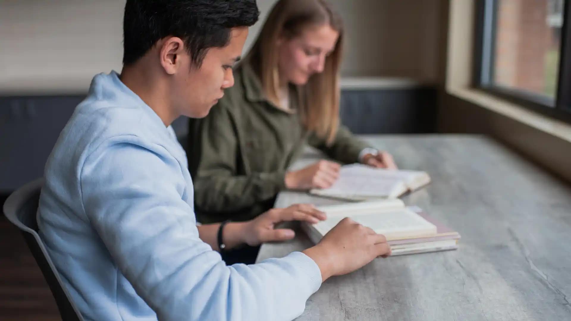 Student-Counseling-Center Two Grace students reading books at a table.