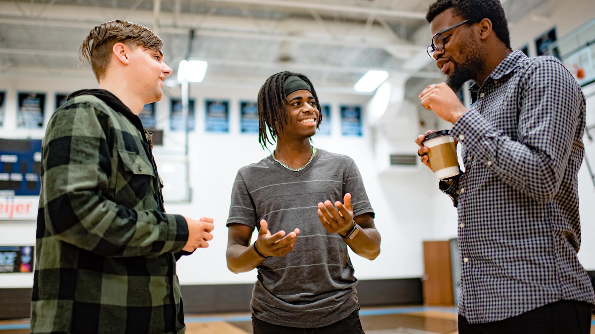 Sports Communication & Management Three male Grace students having a conversation in the Aldrich Athletic Center Gym.
