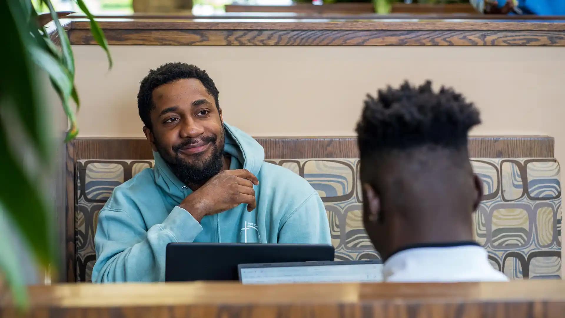 Grace-Apply-Now Happy Grace Student sitting in a booth in the Commons.