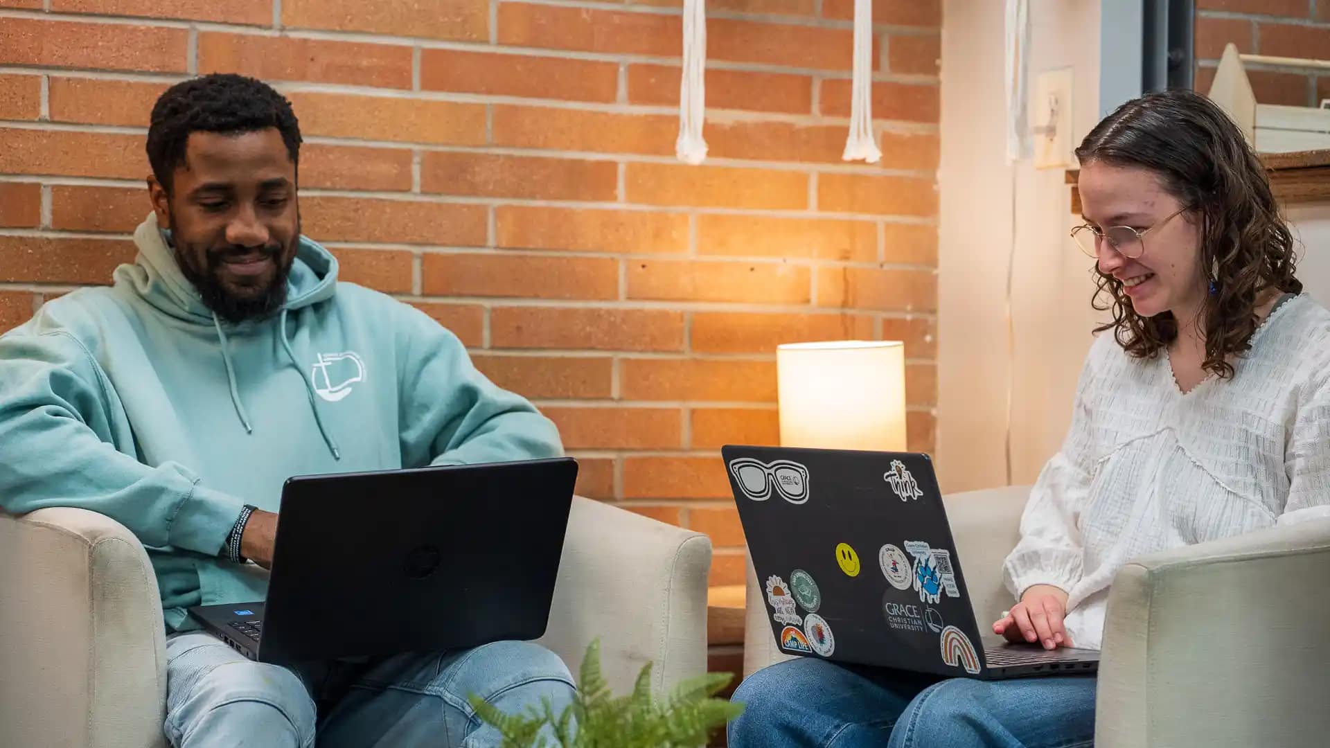 Associate-of-Arts Two Grace students sitting in the Commons working on laptops