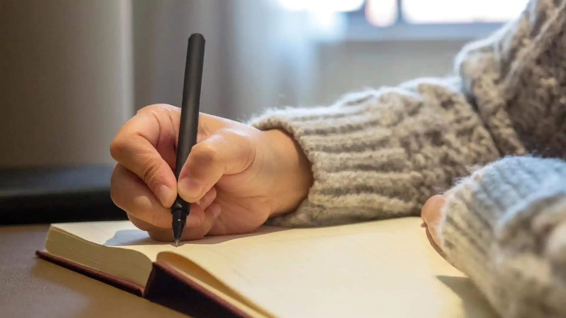 A close up of a hand writing in a notebook