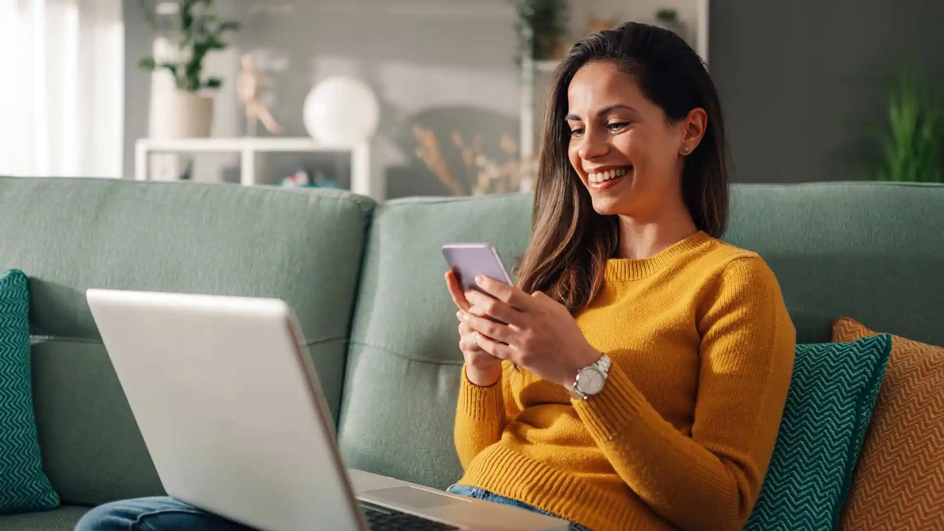 Grace-Online-Student-Laptop2 Happy Grace Online student sitting in their living room, working on a laptop and phone.