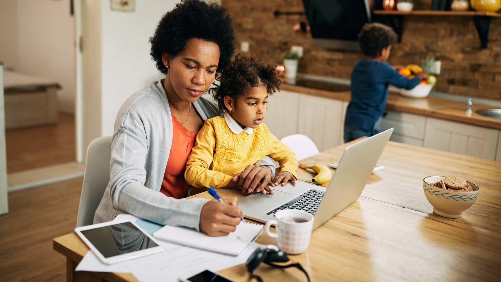 Grace-Online-Student-parent Grace Online Student working on a laptop with a child on her lap.