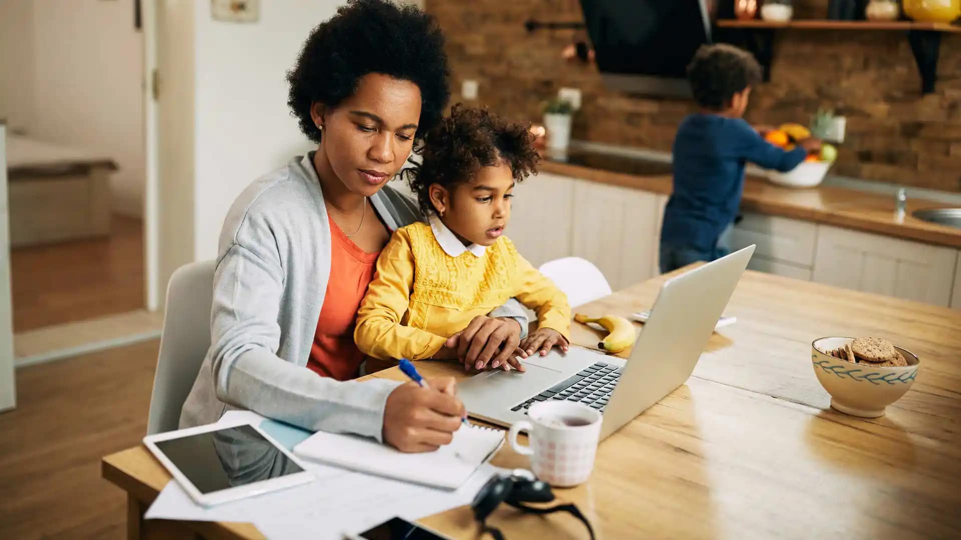 Grace-Online-Student-parent Grace Online Student working on a laptop with a child on her lap.